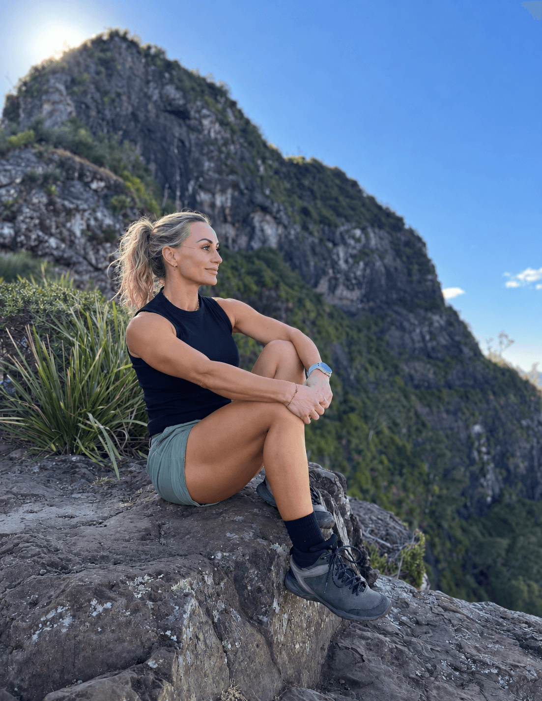 Penny sitting on a rock ledge, looking out across the ranges